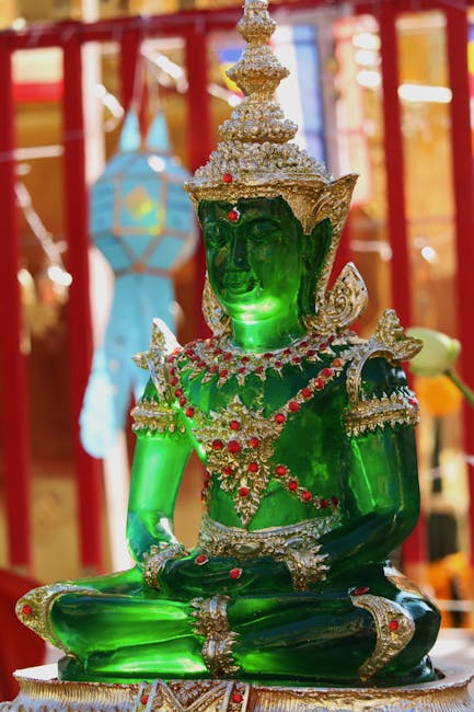 A green statue of buddha sitting on a table