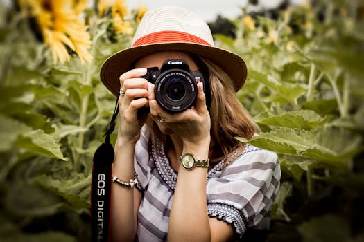 Woman with hat photographing sunflowers in a summer field using a Canon camera.